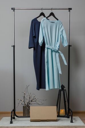 dresses on hanger on garment rack in fashion design studio with mockup box for writing your brandの写真素材