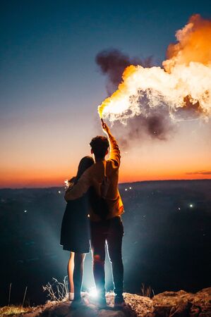 couple and orange smoke grenade on the background of the city lights. evening night timeの写真素材