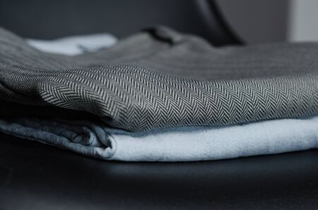 black chair with a stack of new designed clothes in fasion studioの写真素材