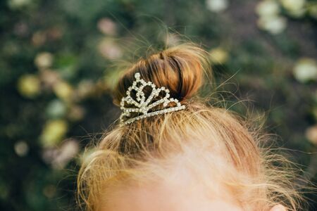 crown on girls head with blurred green leaves on background. being a princess conceptの写真素材