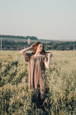 woman in green dress walks on path in wheat field in countrysideの写真素材