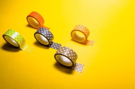 background of colorful washi tapes isolated on yellow backgroundの写真素材