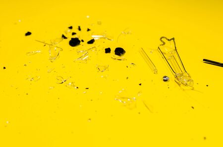 splinters from the glass light bulb isolated on yellow background