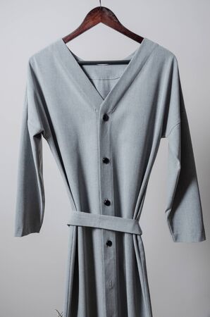 grey long button dress on hanger on garment rack in fashion design studio