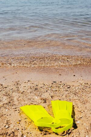 yellow swimming flippers on sand beach by the seaの写真素材