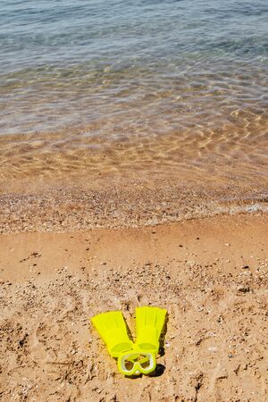 yellow swimming flippers and mask on sand beach by the seaの写真素材