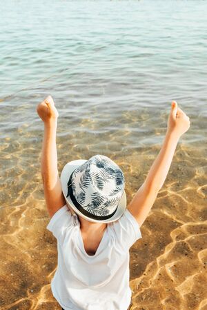 male panama hat on a boy who is sitting at the beach with hands up. kid is happy at summer timeの写真素材