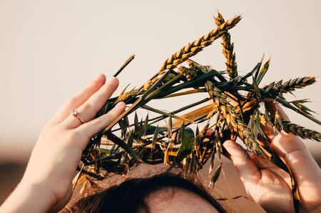 woman punts on her head a wreath made of wheatの写真素材
