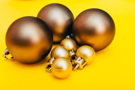 golden christmas tree balls of different sizes. new year decoration in yellow color backgroundの写真素材