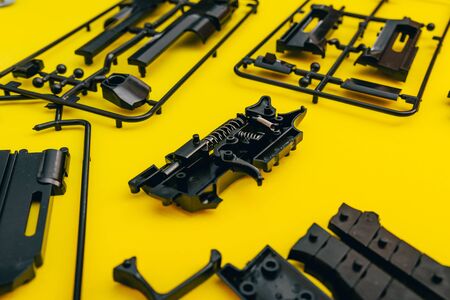 assemble toy handgun with bulllets from the parts concept on yellow background. Plastic model part kits  from top view.の写真素材
