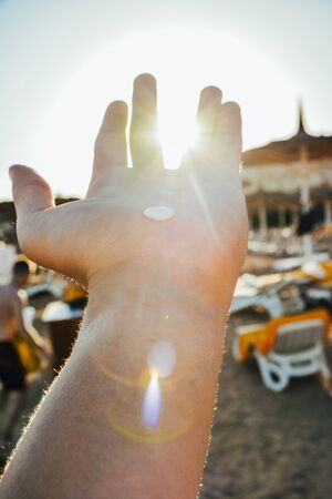 sun breaking between fingers. sunny beach background