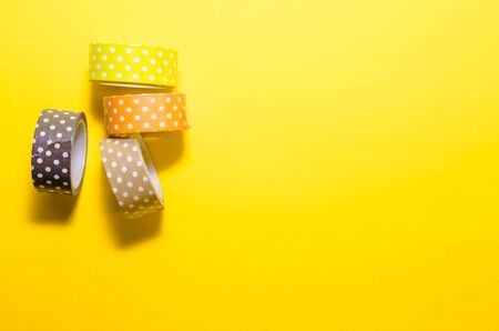 colorful dotted washi tapes isolated on yellow background from top viewの写真素材