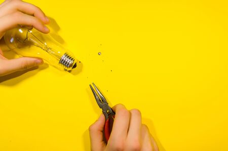 pliers and splinters from the glass light bulb isolated on yellow backgroundの写真素材