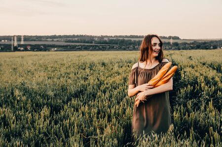 close up photo of woman holds freshmade french baguettes in wheat fieldの写真素材