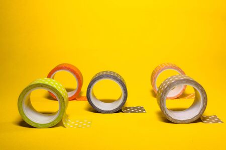 colorful dotted washi tapes isolated on yellow background from side viewの写真素材
