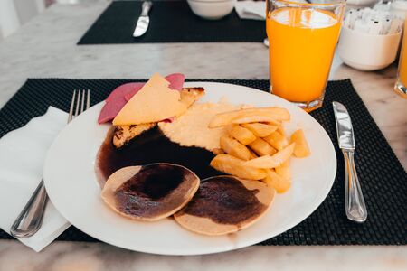 breakfast in hotel. plate with french fries and pancakes with orange lemonadeの写真素材