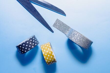 colorful washi tapes isolated on blue background with opened scissorsの写真素材