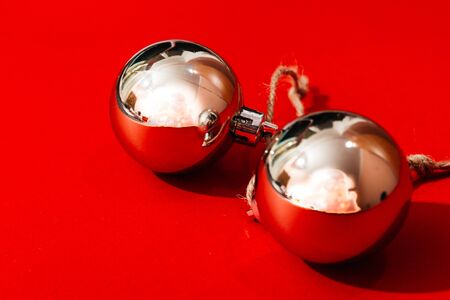 two red christmas tree balls isolated on red background from top view. christmas vibes