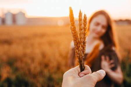 close up photo of happy woman in dress standing in green wheat field