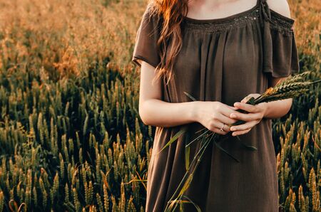 woman in dress stands in green wheat meadowの写真素材