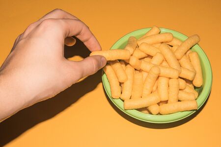 hand taking a puff cheese corn snack from a bowlの写真素材