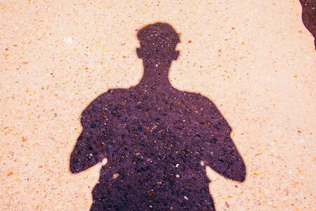 mans black shadow on the ground taking a photoの写真素材