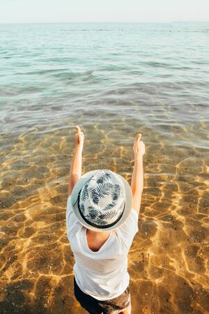 male panama hat on a boy who is sitting at the beach with hands up. kid is happy at summer timeの写真素材