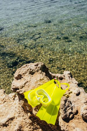 yellow swimming mask with flippers on sand beach by the seaの写真素材