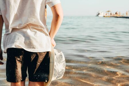 male panama hat in hand of little boy at the beachの写真素材