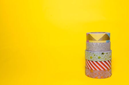tall line of colorful washi tapes isolated on yellow background. school stationeryの写真素材
