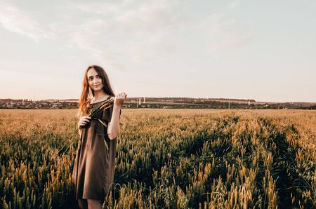 happy woman walking in wheat field during sunriseの写真素材