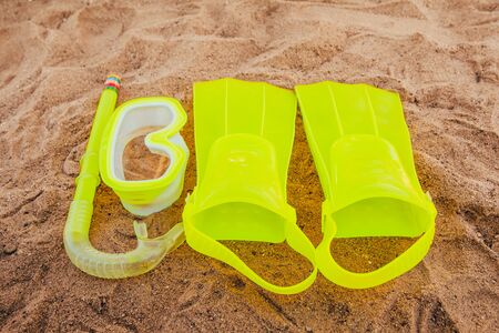 yellow swimming flippers with mask and tube on sand beachの写真素材