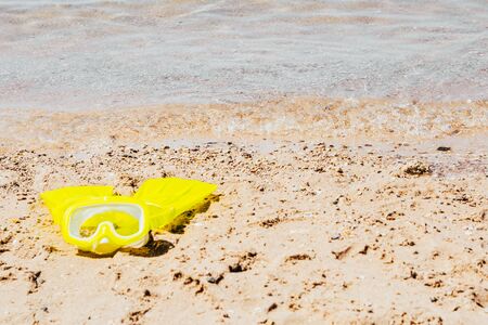 yellow swimming mask with flippers on sand beach by the seaの写真素材