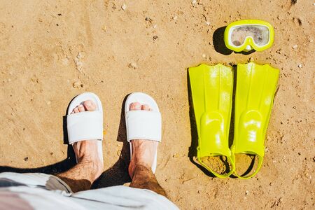yellow swimming flippers with mask and tube on sand beach by the clear seaの写真素材
