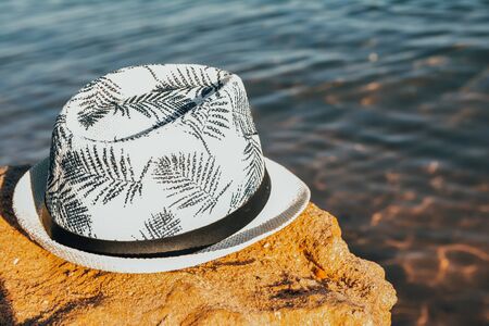 male panama hat on a big stone  at the beach