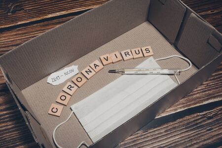 Novel coronavirus infection written with wooden letters. breathing mask, thermometer and pills isolated. symptoms of the virus "2019-nCoV"の写真素材