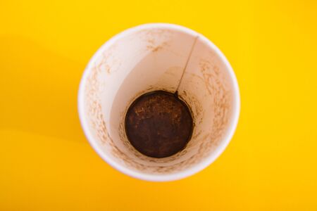 dirty coffee takeaway cup isolated on yellow backfround from top viewの写真素材