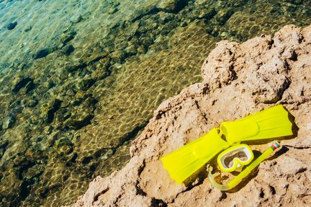 yellow swimming mask with flippers on sand beach by the seaの写真素材