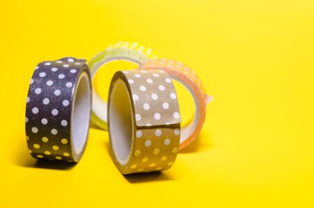 a mess of colorful washi tapes isolated on yellow background. femenine stationeryの写真素材