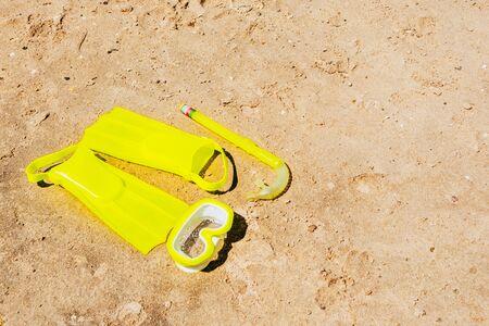 yellow swimming flippers with mask and tube on sand beachの写真素材