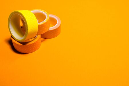 a mess of colorful washi tapes isolated on yellow background. school stationeryの写真素材