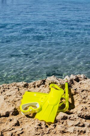 yellow swimming flippers with mask and tube on sand beach by the seaの写真素材