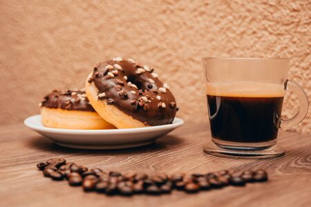 americano and chocolate donuts on the coffee shop tableの写真素材
