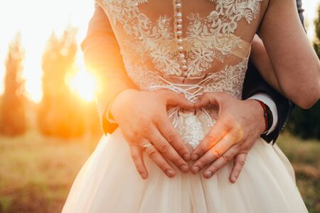 heart with hands in front of brides back on wedding day. selective focus