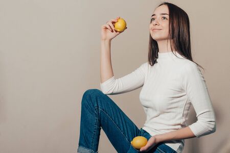 smiling girl in a white turtleneck with lemons looks awayの写真素材