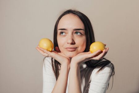 happy girl holding lemons in her hands and dreaming of something  . close upの写真素材