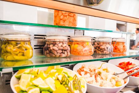 close up view of buffet table with salads and  beans in big white plates. hotel dinning room