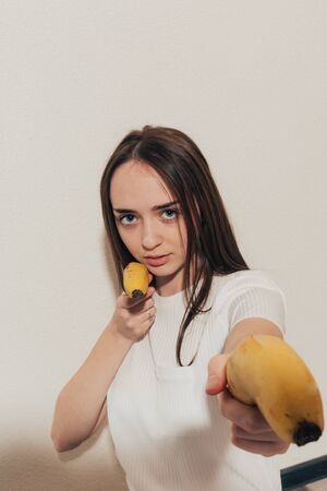 girl with banana pistols looks at the camera with an angry lookの写真素材