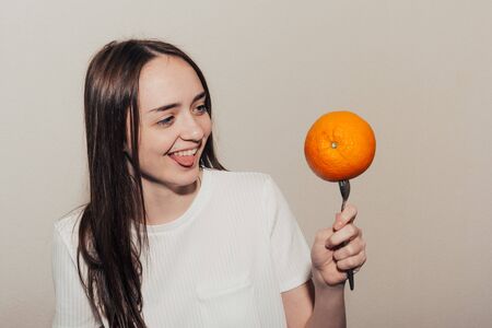 girl with an appetite looks at an orange on a fork. proper nutrition and diet concept.の写真素材