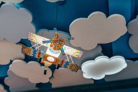 handmade lamp in the form of a colored paper airplane that flies on the ceiling from clouds .の写真素材
